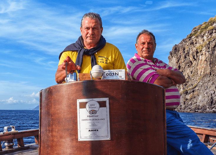 Salvo Puglisi e suo padre Mario al timone di U Cammellu N'ammuratu, con sullo sfondo la costa eoliana